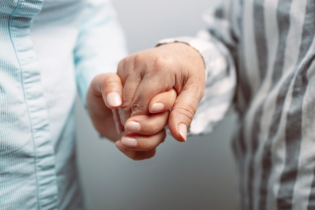 Caregiver, carer hand holding elder hand in hospice care background, closeup. Happy mother's day.