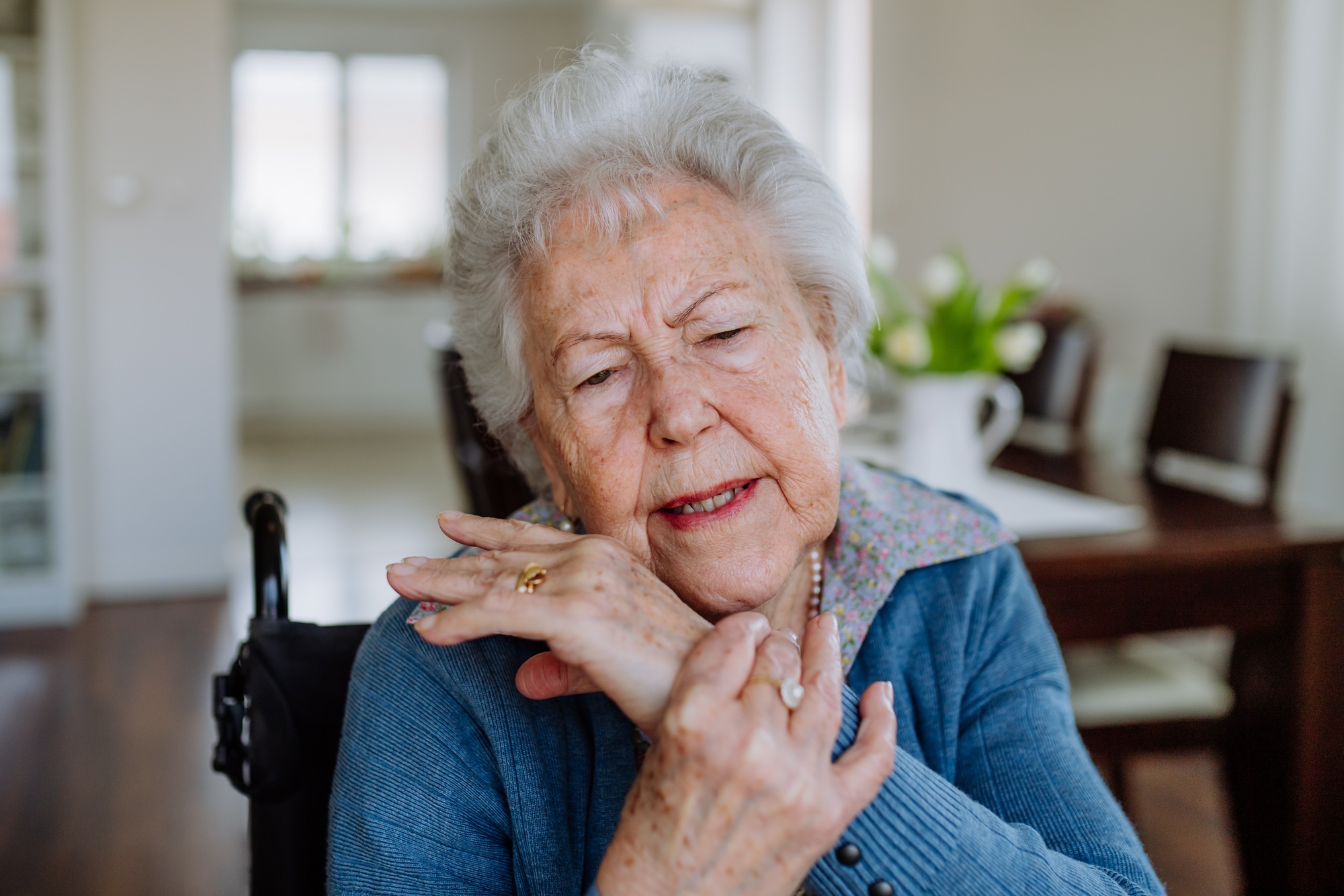 Portrait of senior woman on wheelchair with pain in her hand.